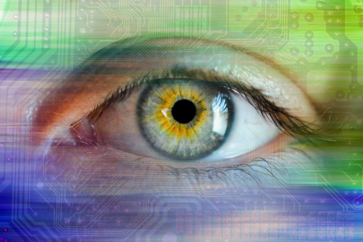 Foto: Menschliches Auge in bunten Farben mit einer Leiterplatte als Hintergrund