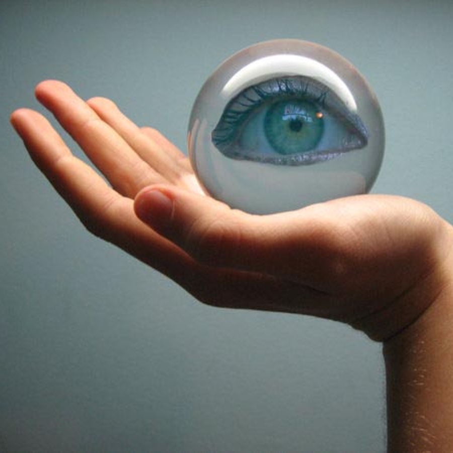Bild: Glaskugel mit einem Auge auf einer Hand