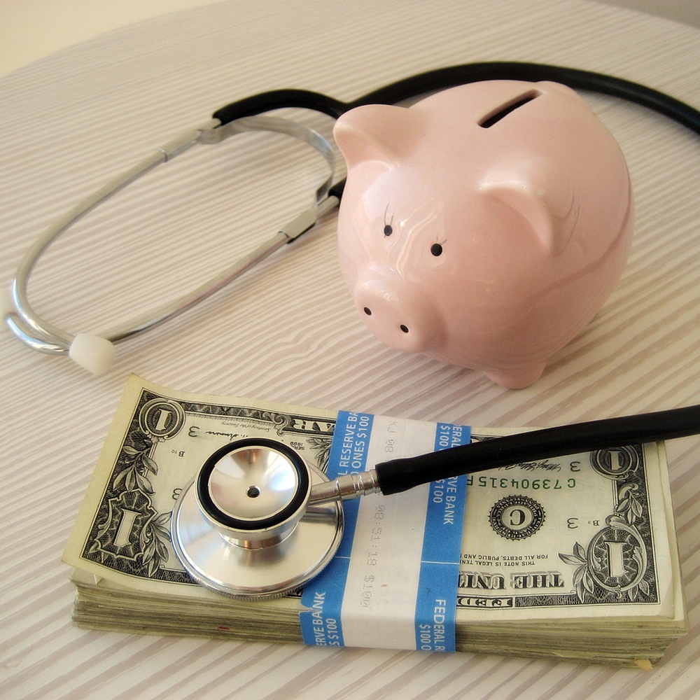 Foto: Sparschwein mit Stetoskop und einem Bündel Dollarnoten