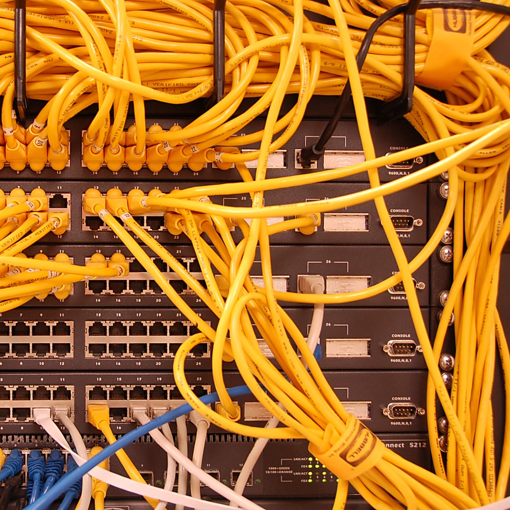 Foto: Gestapelte 24 Port-Switches mit vielen mehrheitlich gelben Netzwerk-Kabeln