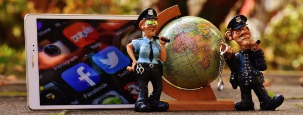 Bild: Facebook-Polizisten (zwei kleine Polizisten-Figuren, die vor einem Globus sowie einem Tablet mit unter anderem Facebook-Symbol stehen)