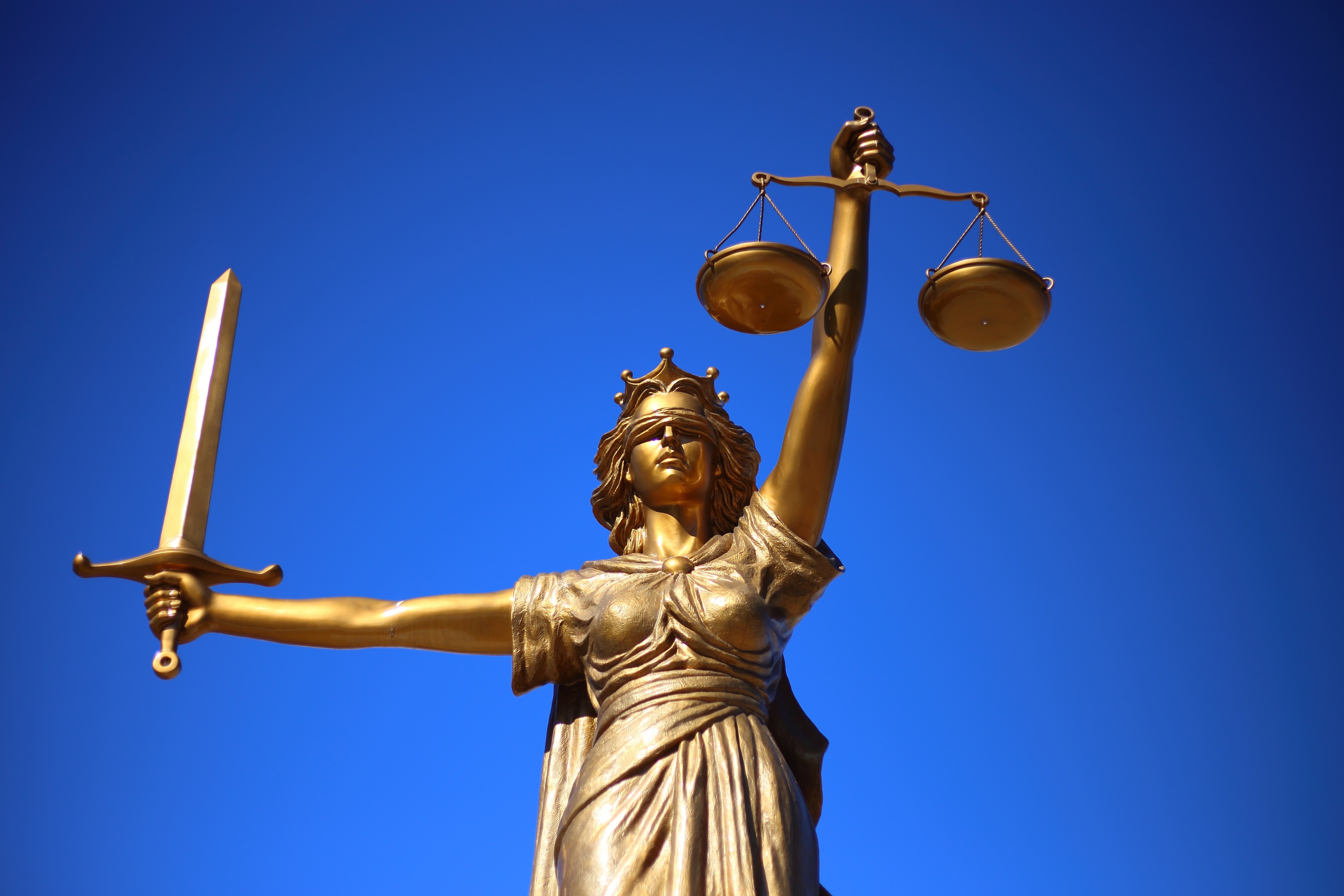 Bild: Justitia mit verbundenen Augen vor blauem Hintergrund