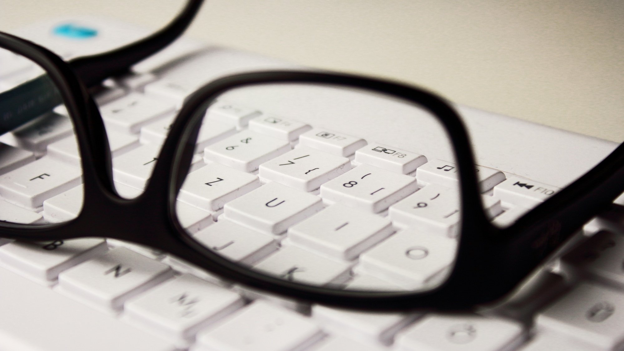Foto: Schwarze Brille, die auf einer weissen Tastatur liegt