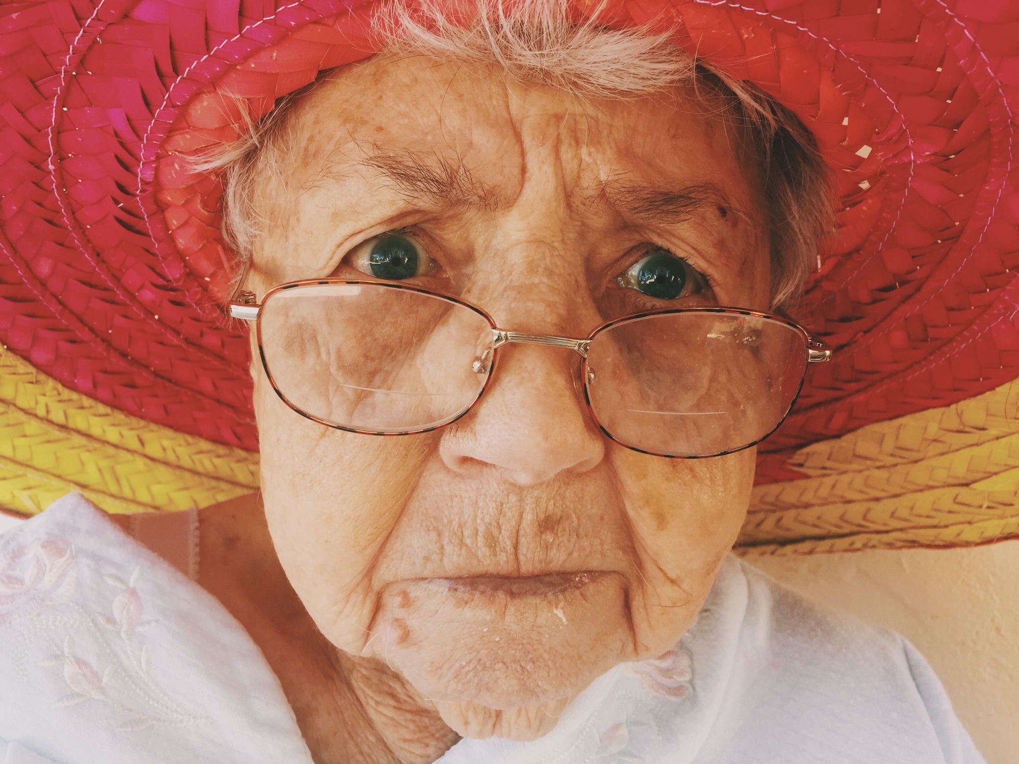 Foto: Seniorin mit Brille und rotem Hut (Porträtfoto)