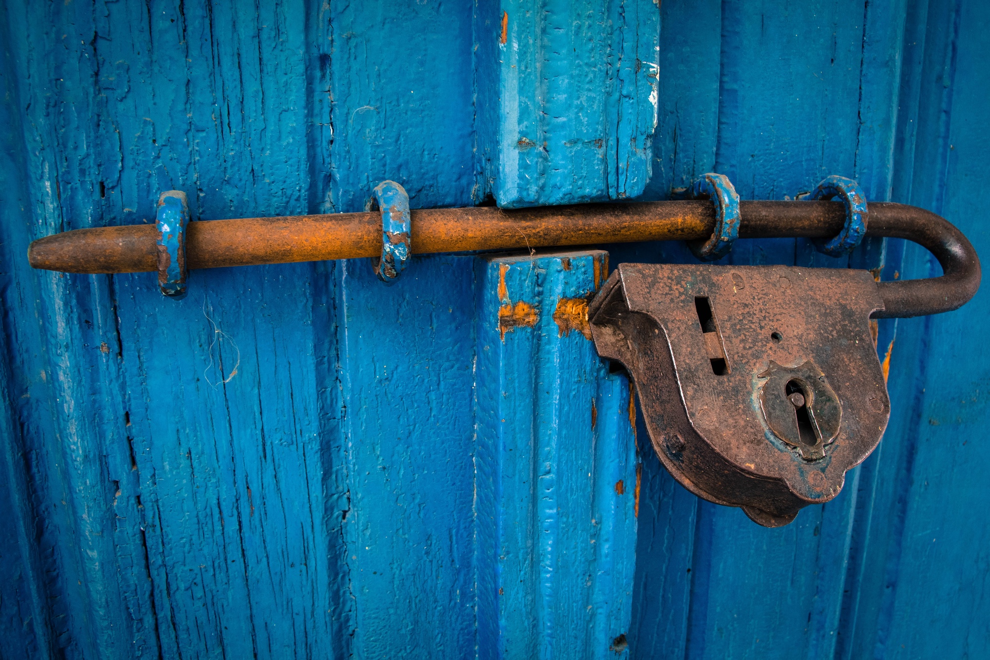 Foto: Rostiges Vorhängeschloss an blauer Holztüre