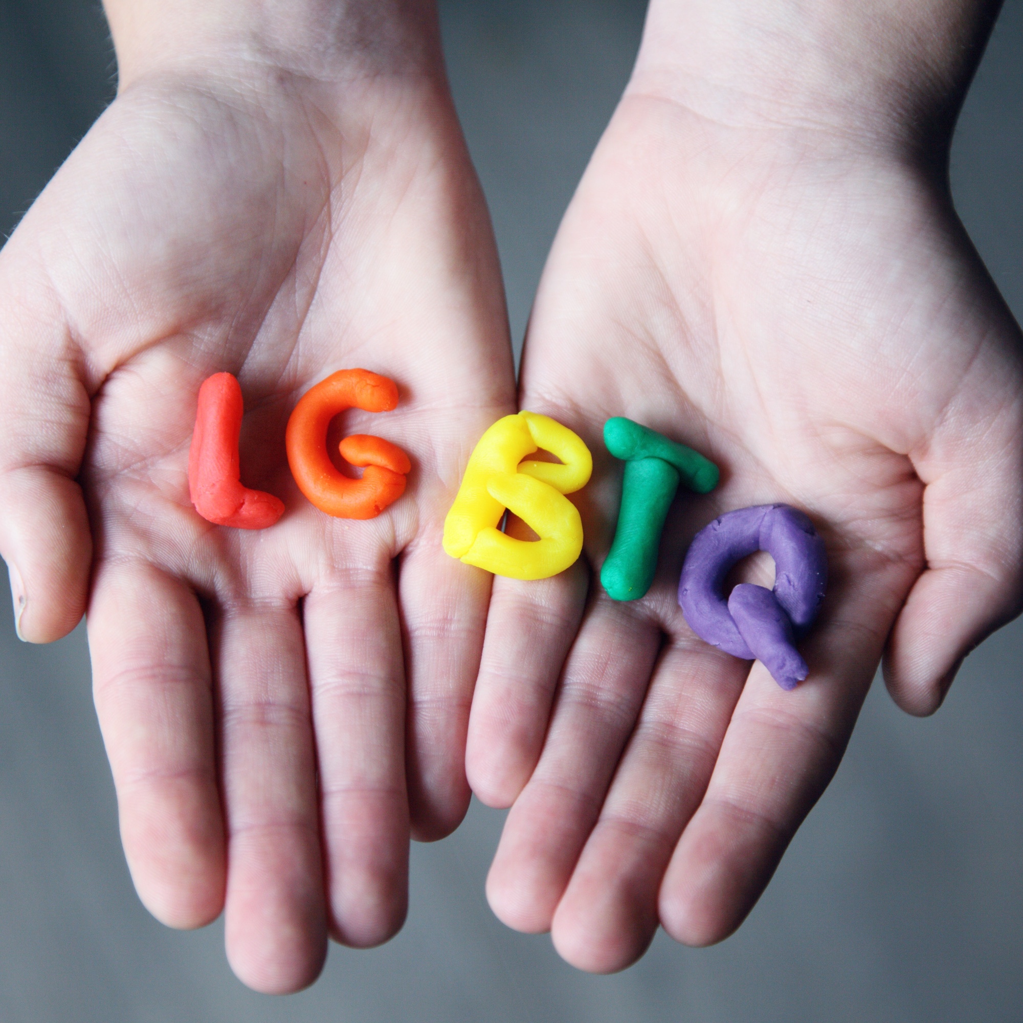 Foto: Ausgestreckte Hände, auf denen die Grossbuchstaben LGBTQ in Regenbogen-Farben liegen